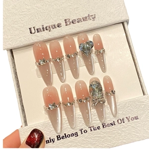 Press-on nail set with pink gradient, heart gems, and crystal bow design in a box