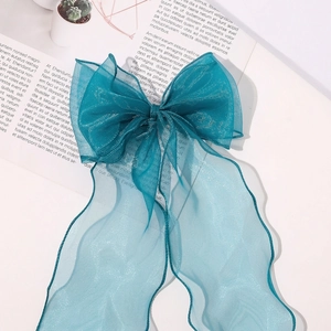 Detail of teal organza ribbon hair clip showing layered bow texture and long wavy streamers