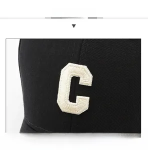 Close-up of the white embroidered letter C on a black cotton twill baseball cap