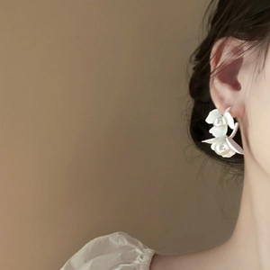 French style white C-shaped flower earrings with pearls on model's ear
