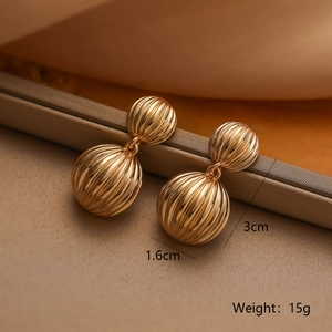Close-up of gold-plated geometric sphere earrings with vertical textured vertical ribs