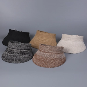 Cinq visières en tricot noir, beige, kaki et gris chiné disposées à plat sur fond gris