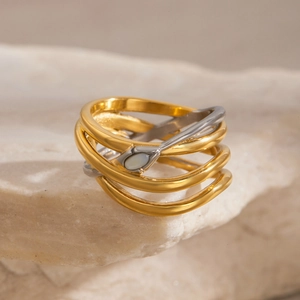 Detail of layered wrap ring in gold and silver finish on a natural stone base