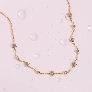 Close-up of golden necklace featuring floral pendants and white zircon crystals
