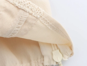 Close-up of beige lace fabric texture and zipper detail on the corset camisole