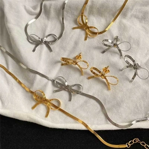 Vue détaillée de l'ensemble de bijoux nœud papillon doré et argenté avec colliers et boucles