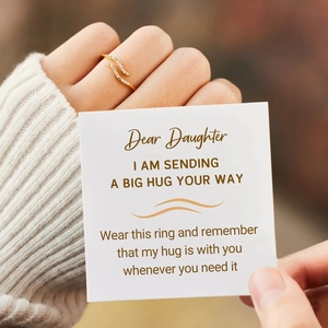 Close-up of wavy gold ring with zircons and an English message greeting card