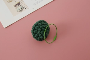 Macro detail of handmade green knitted vegetable pendant with steel wire keyring