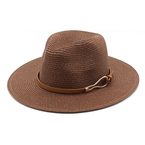 Close-up of wide brim straw hat featuring a brown leather band and gold buckle