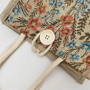 Detail of linen tote bag with vintage floral print, wooden button and braided rope handle