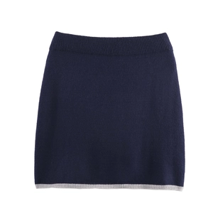 Dettaglio di una gonna in maglia blu scuro con bordo a strisce grigie a contrasto