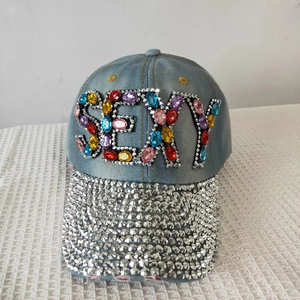 Close-up of light blue denim cap with colorful SEXY rhinestones and diamond-studded brim