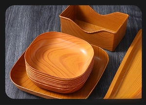 Detail of stacked square plates and long tray with natural wood grain texture