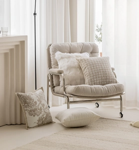 Detail of luxury beige throw pillows on a modern metal armchair by a bright window