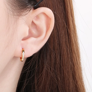 Detail of gold-plated hoop earrings with white zircon inlay worn by a model