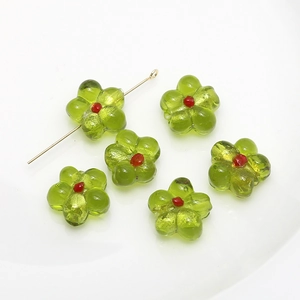 Macro shot of green glass flower beads with red centers for DIY jewelry making