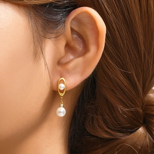 Detail of 925 silver pearl drop earring with gold finish on a model showing fine texture