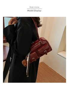 Detail of dark red patent leather shoulder bag with bear pendant and scarf on black coat