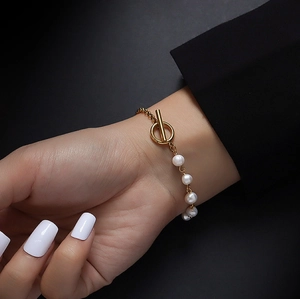 Detailed close-up of a French baroque pearl bracelet with gold chain and T-bar clasp closure