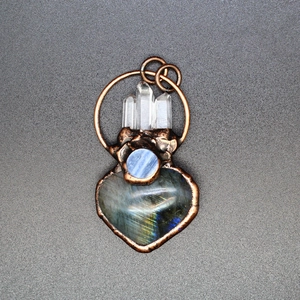 Macro shot of handmade copper heart pendant with labradorite and moonstone inlay