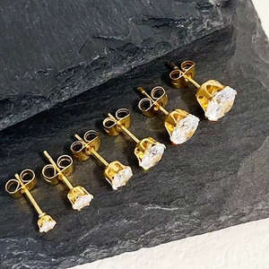 Set of six round-cut cubic zirconia stud earrings in varying sizes on stone surface