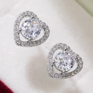 Macro shot of heart-shaped zircon earrings with polished silver finish and pavé setting