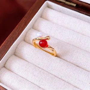 Eleganter 18K vergoldeter Ring mit Süßwasserperle und rotem Achat auf Samttablett