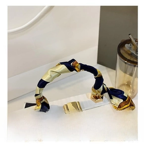 Detail of white box bag handle wrapped in a yellow and blue printed silk scarf