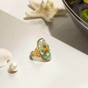 Detail of starfish ring with blue shell inlay and pearl accents on golden band