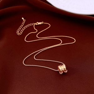 Close-up of 18k rose gold plated cylinder pendant necklace on red velvet fabric