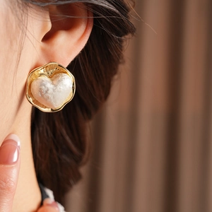 Détail d'une boucle d'oreille cœur plaquée or 16 carats portée par un mannequin de près