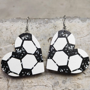 Macro detail of heart-shaped faux leather earrings with a black and white soccer pattern