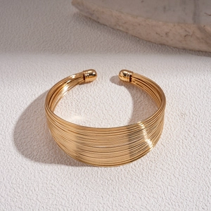 Detail of a golden multi-layer metallic cuff bracelet with smooth parallel wires