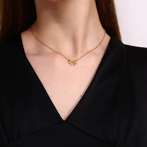 Close-up of elegant 18k gold-plated bow pendant necklace on model with black V-neck