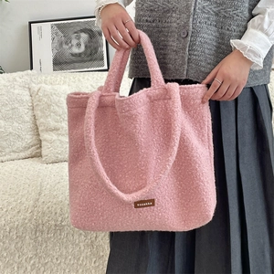 Detailed close-up of pink plush teddy fleece tote bag with brown leather brand label