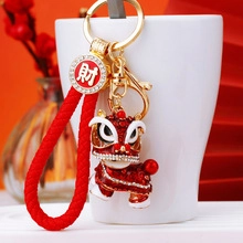 Close-up of red rhinestone Kirin keychain with woven rope on a white porcelain cup
