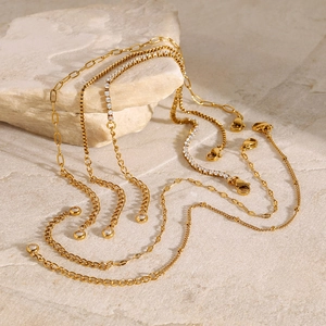 Elegant gold stainless steel chains with zircon stones on natural stone background
