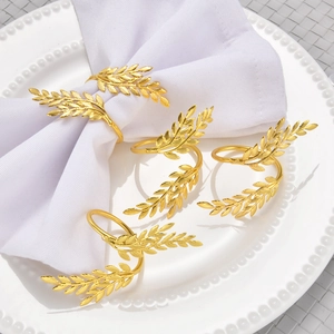 Set of 6 golden wheat ear napkin rings in leaf design displayed on a white plate