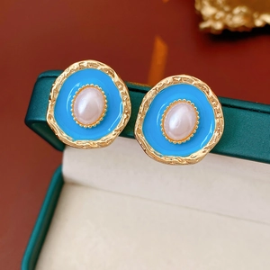 Macro shot of vintage blue enamel earrings with gold trim and central pearl detail