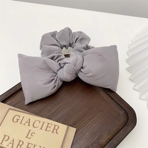 Close-up of a grey cotton bubble bow scrunchie on a dark wooden display tray
