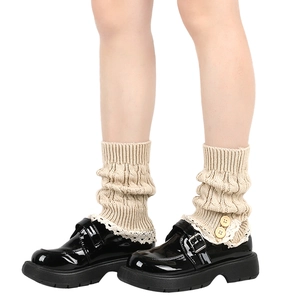 Close-up of beige knitted leg warmers with delicate lace trim and wood buttons