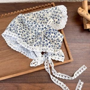 Detail of baby floral cotton hat with blue flower patterns and white lace trim