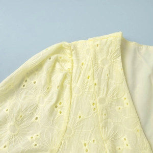 Detail of yellow cotton mini dress featuring floral eyelet embroidery and puff sleeves