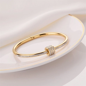 Elegant gold titanium steel bracelet with sparkling diamond cylinders on a white porcelain dish