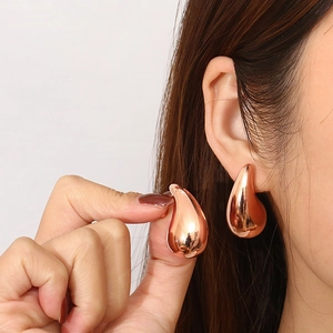 Detailed view of chunky rose gold teardrop earrings showing high-shine metal texture