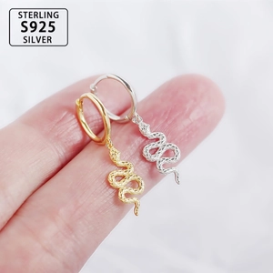 Macro shot of S925 sterling silver snake earrings in gold and silver on hand