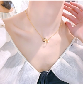 Close-up of 18k gold-plated interlocking heart pendant necklace on female model neck