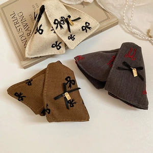 Detailed fabric texture of bow hair clips with embroidery and gold metal pendants