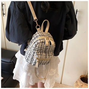Detailed back view of a mini tweed plaid backpack with gold hardware worn by a model