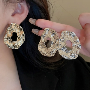 Detail of metallic textured geometric earrings with hammered finish on female model